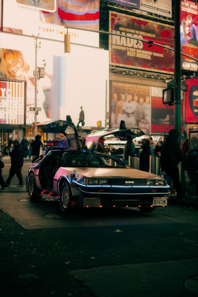 A classic DeLorean DMC-12 with open doors in a vibrant city night scene.